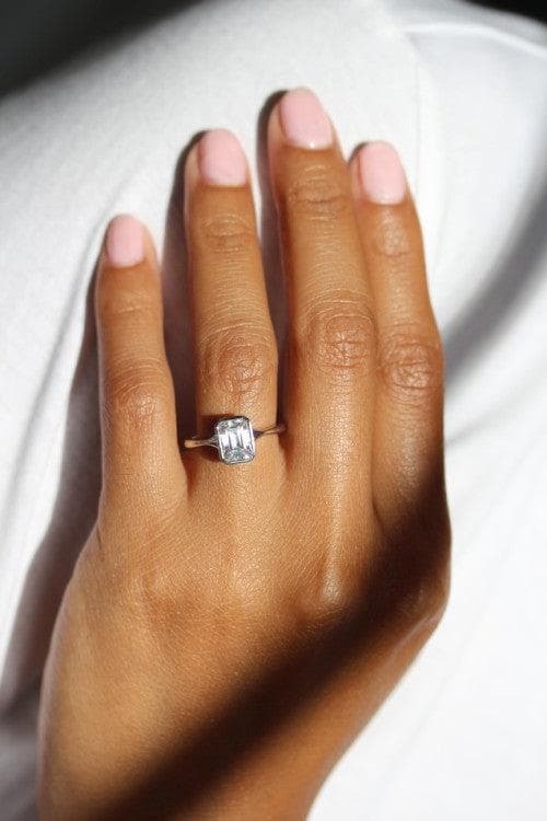Emerald-cut diamond Stevie bezel ring on a hand