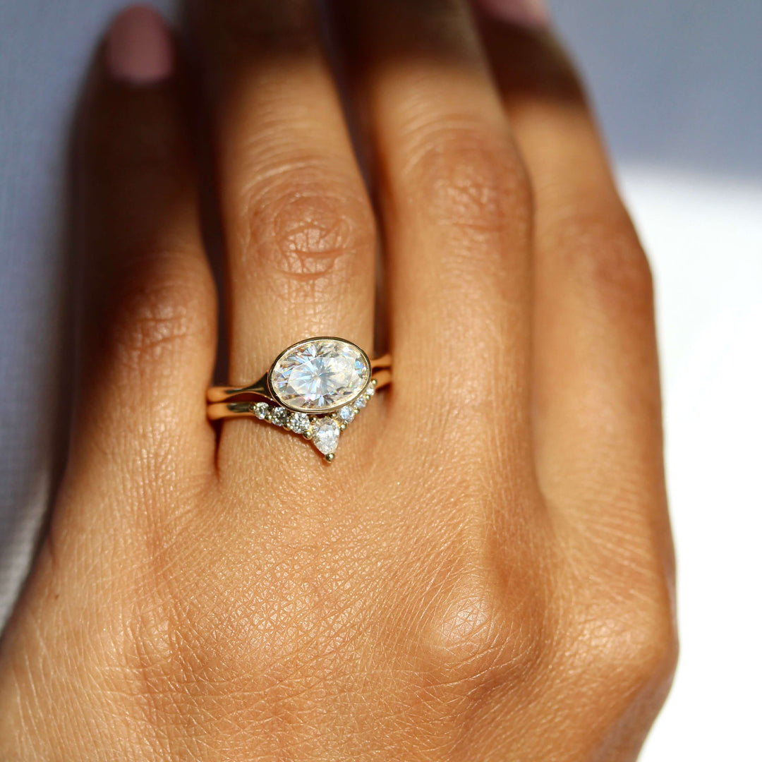 The Stevie Ring (East-West Oval) in Yellow Gold stacked with the Pinnacle wedding band in yellow gold modeled on a hand