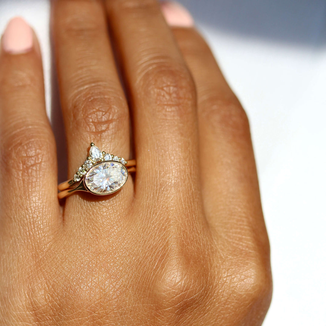 The Stevie Ring (East-West Oval) in Yellow Gold stacked with the Pinnacle wedding band in yellow gold modeled on a hand