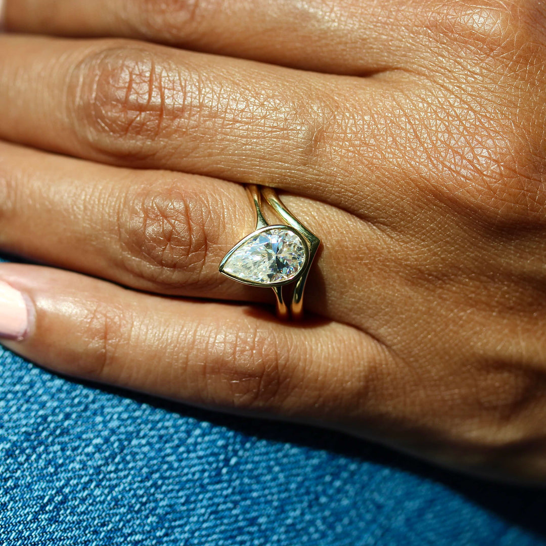 The Stevie Ring (Pear) in Yellow Gold stacked with the V wedding band in yellow gold modeled on a hand