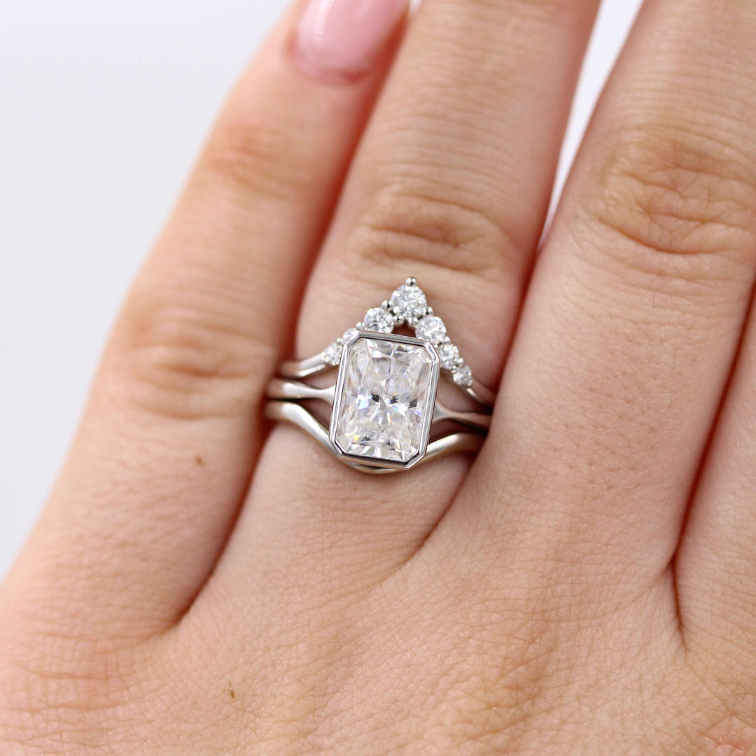 The Stevie Ring (Radiant) in White Gold with 2ct Moissanite stacked with the Graduated Diamond V-Band and the Wave Band in white gold modeled on a hand