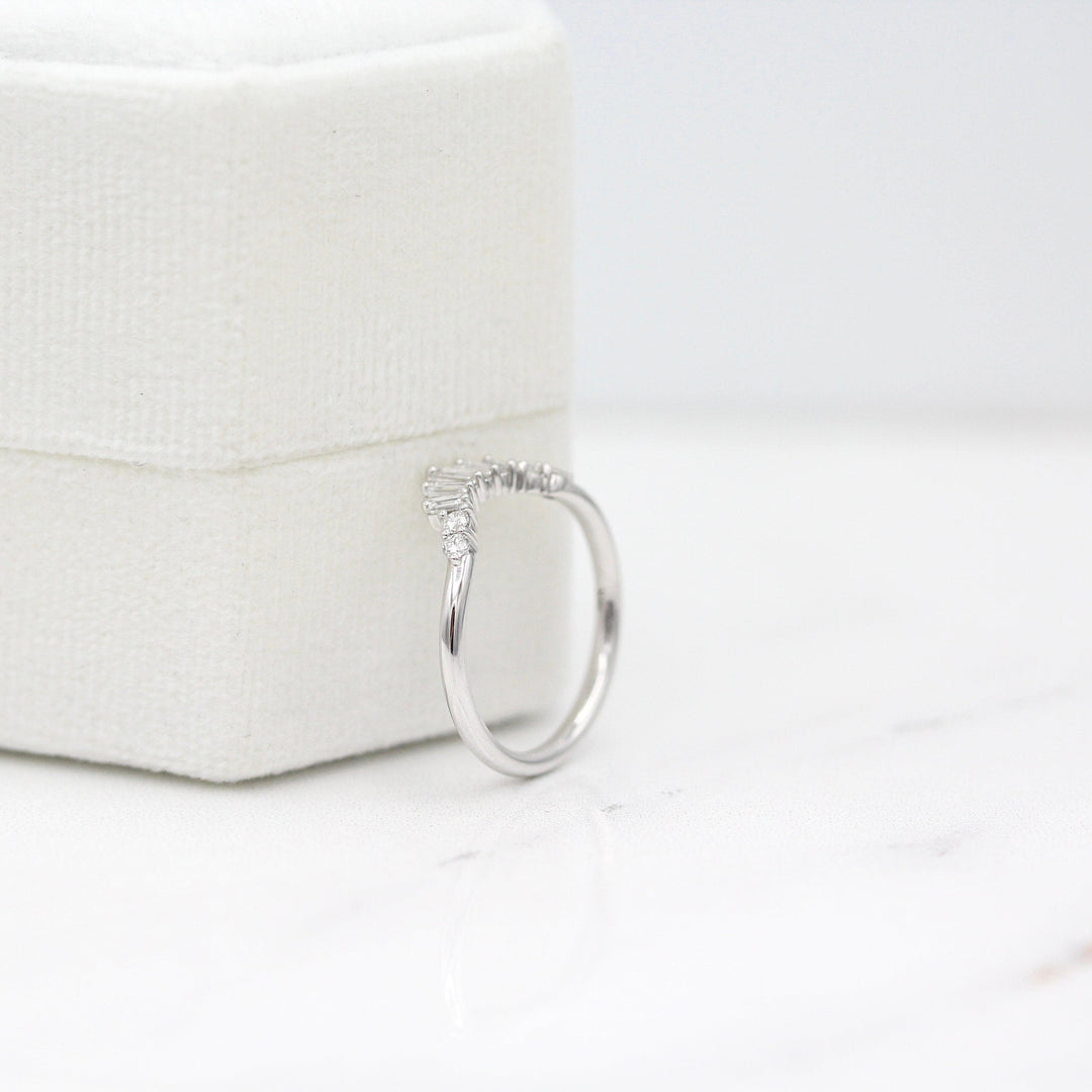 The Sunburst Wedding Band in White Gold leaning against a white velvet ring box