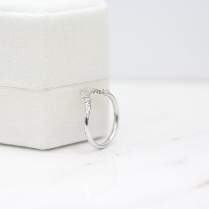 The Sunburst Wedding Band in White Gold leaning against a white velvet ring box