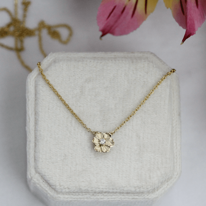 a poppy gold necklace on a white velvet box