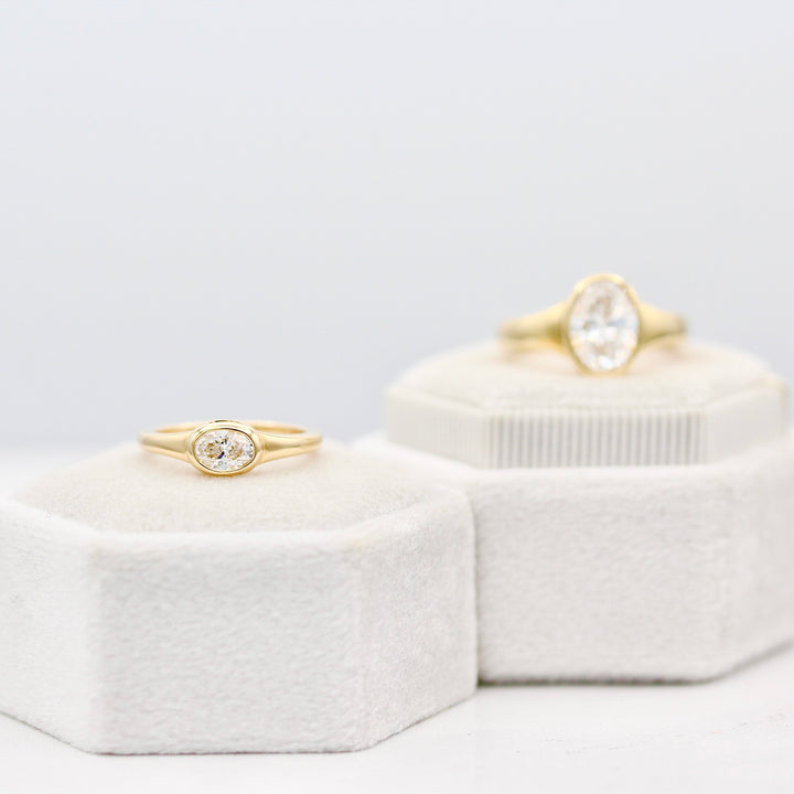 Baby Billie East-West Oval in Yellow Gold with the Original Billie Oval in the background