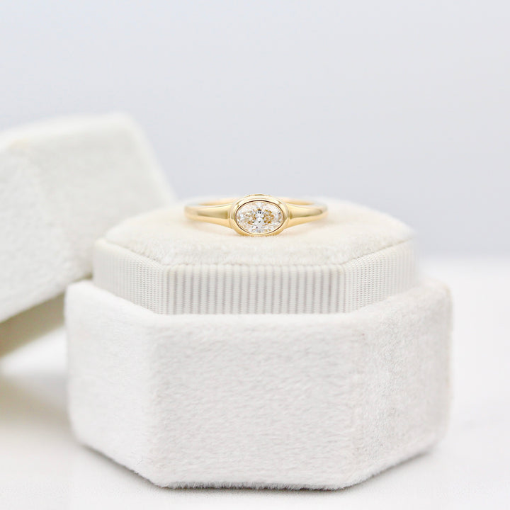 Bezel set East-West Diamond Oval Pinky Ring in Yellow Gold on a White Ring Box