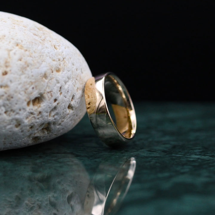Sleek and modern yellow gold band leading on a white rock with black background