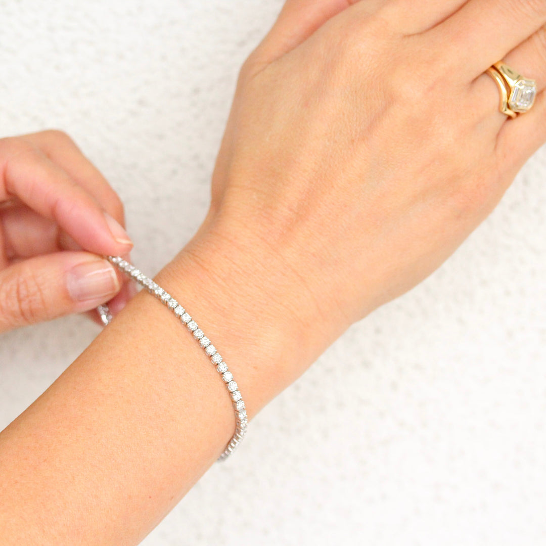 The Classic Diamond Tennis 
Bracelet in white gold shown on hand against a white background 