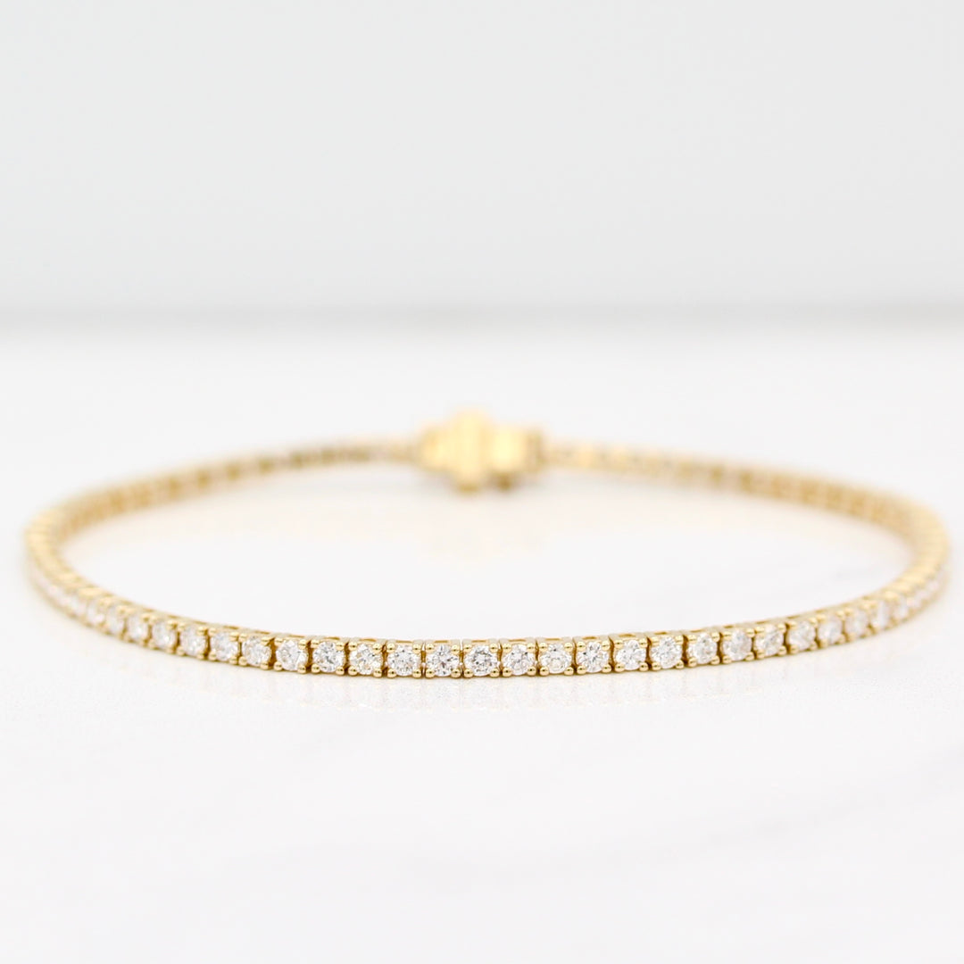 Diamond tennis bracelet in yellow gold on a white background