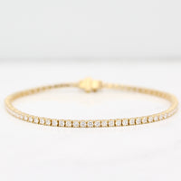 Diamond tennis bracelet in yellow gold on a white background