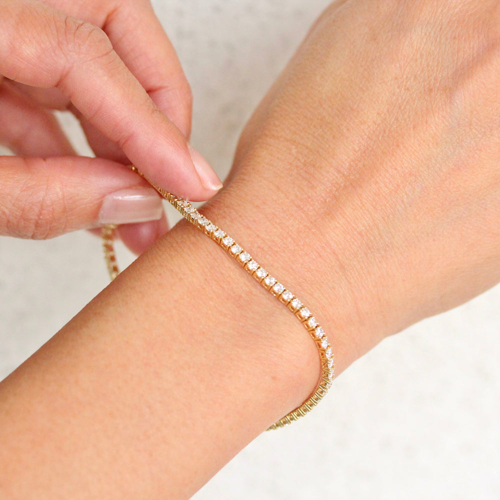 Yellow gold round diamond tennis bracelet on a hand