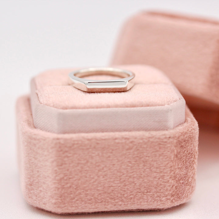 Silver bar signet ring on a pink ring box on a light background