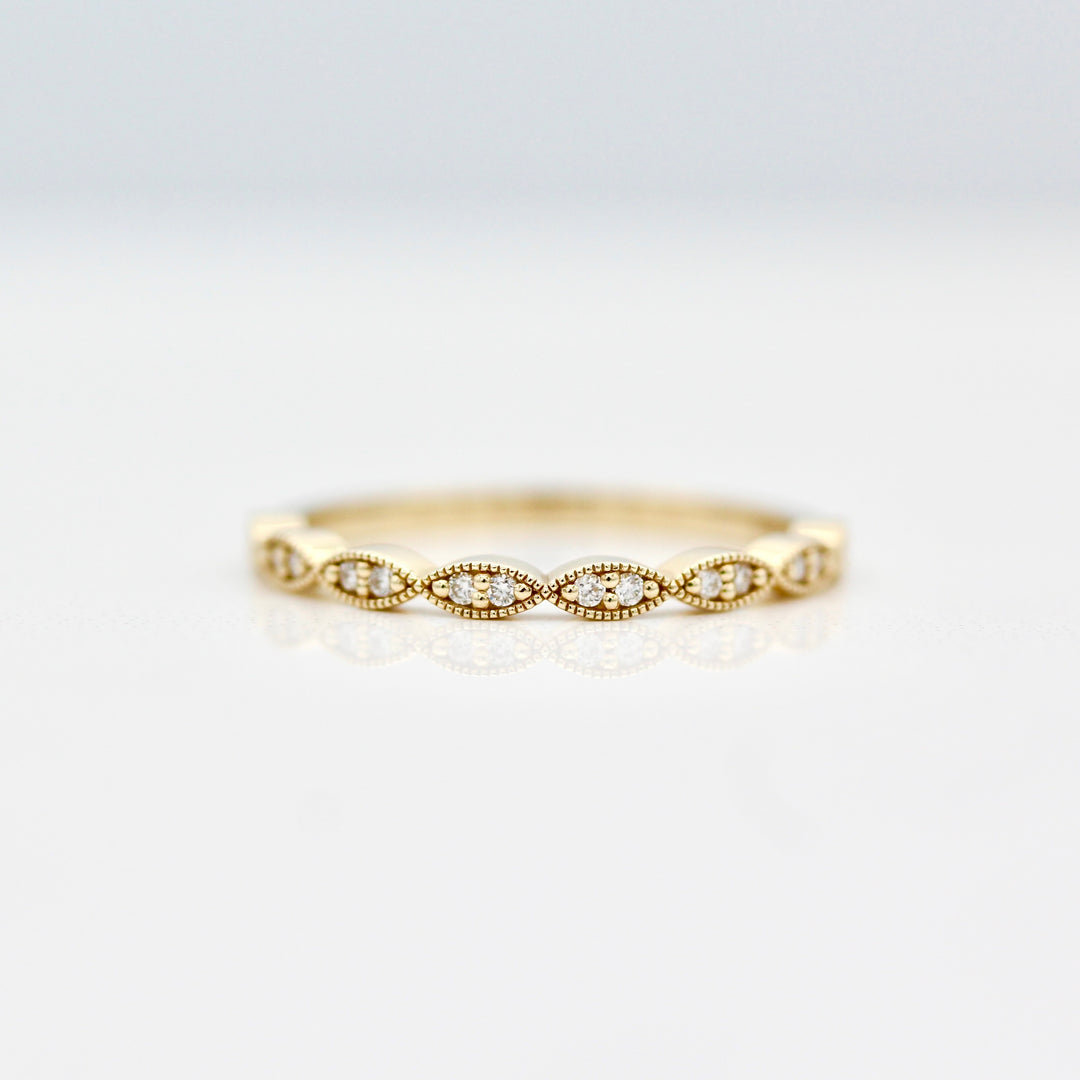 Twisty milgrain wedding band with round diamonds in yellow gold on a white background