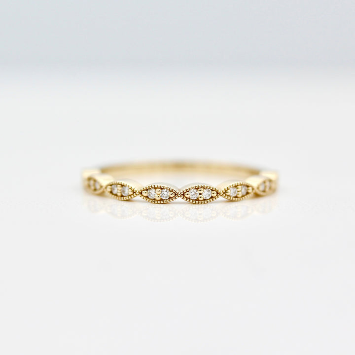 Twisty milgrain wedding band with round diamonds in yellow gold on a white background