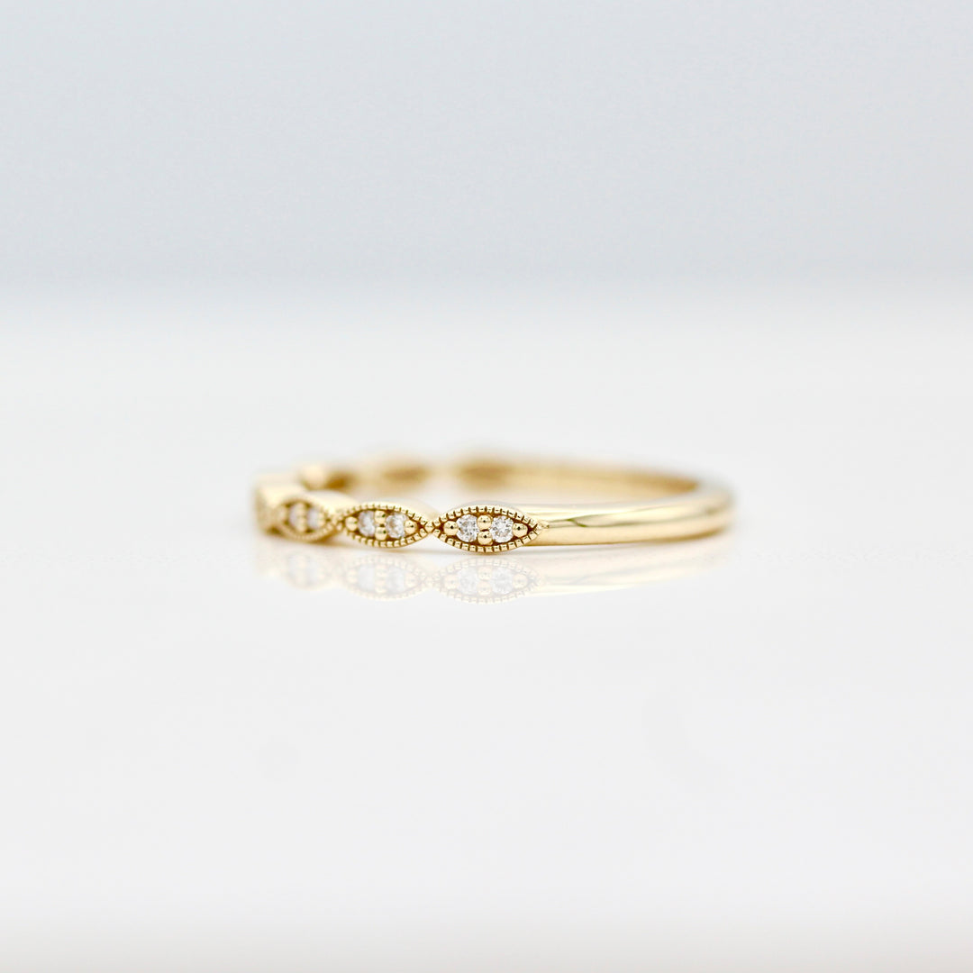 Yellow gold wedding band with round diamonds and milgrain on a white background