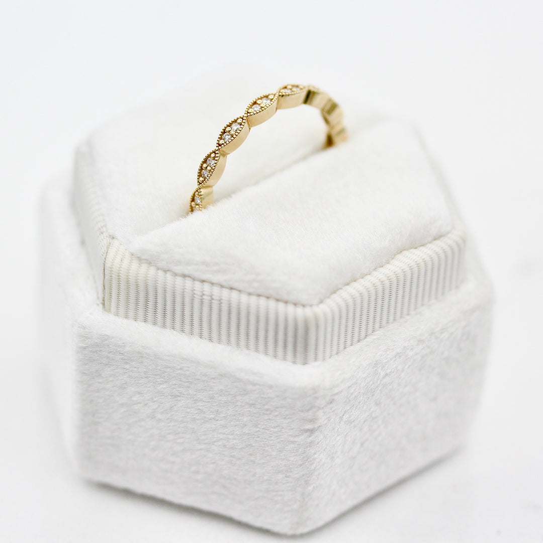 The Isla Wedding Band with round diamond and milgrain details angled in a white velvet ring box against a white background