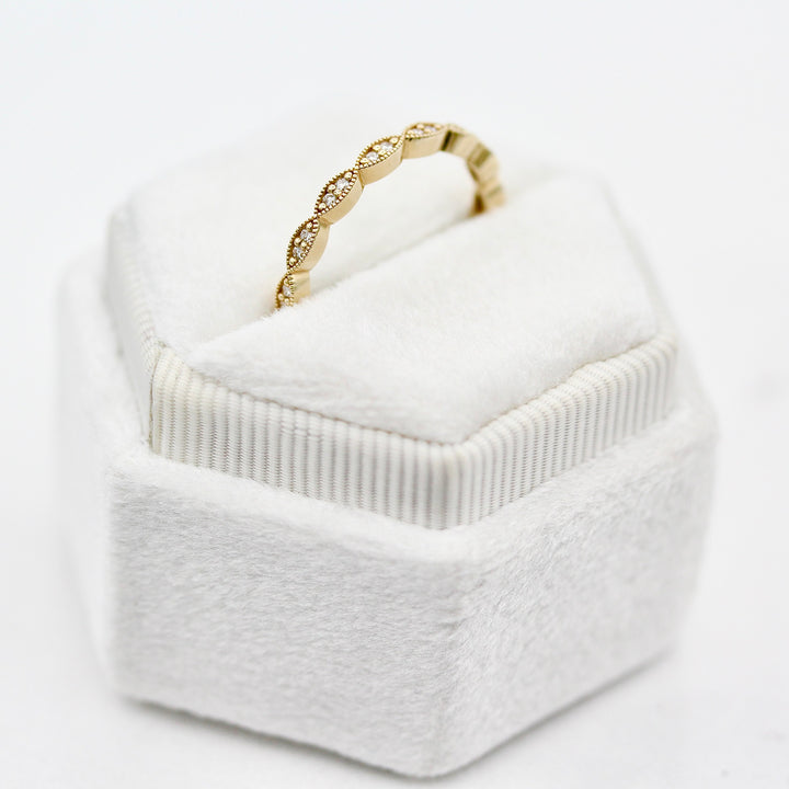 The Isla Wedding Band with round diamond and milgrain details angled in a white velvet ring box against a white background