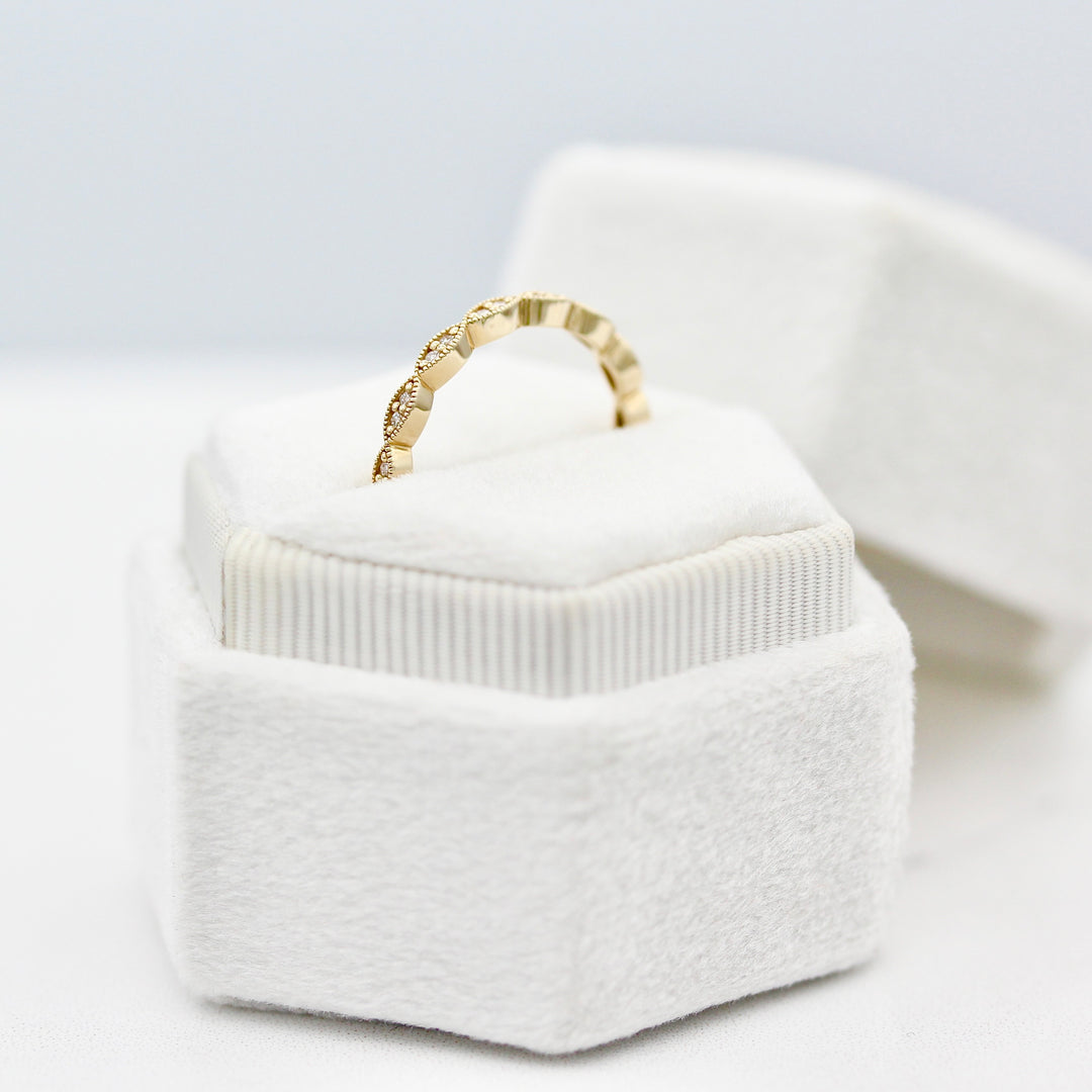 A profile view of The Isla Wedding Band in yellow gold in a white velvet ring box