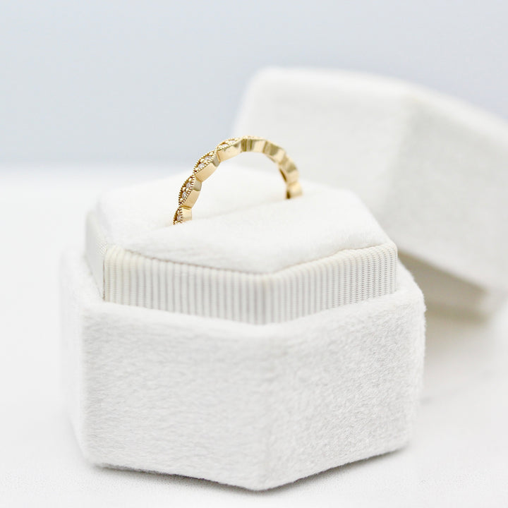A profile view of The Isla Wedding Band in yellow gold in a white velvet ring box