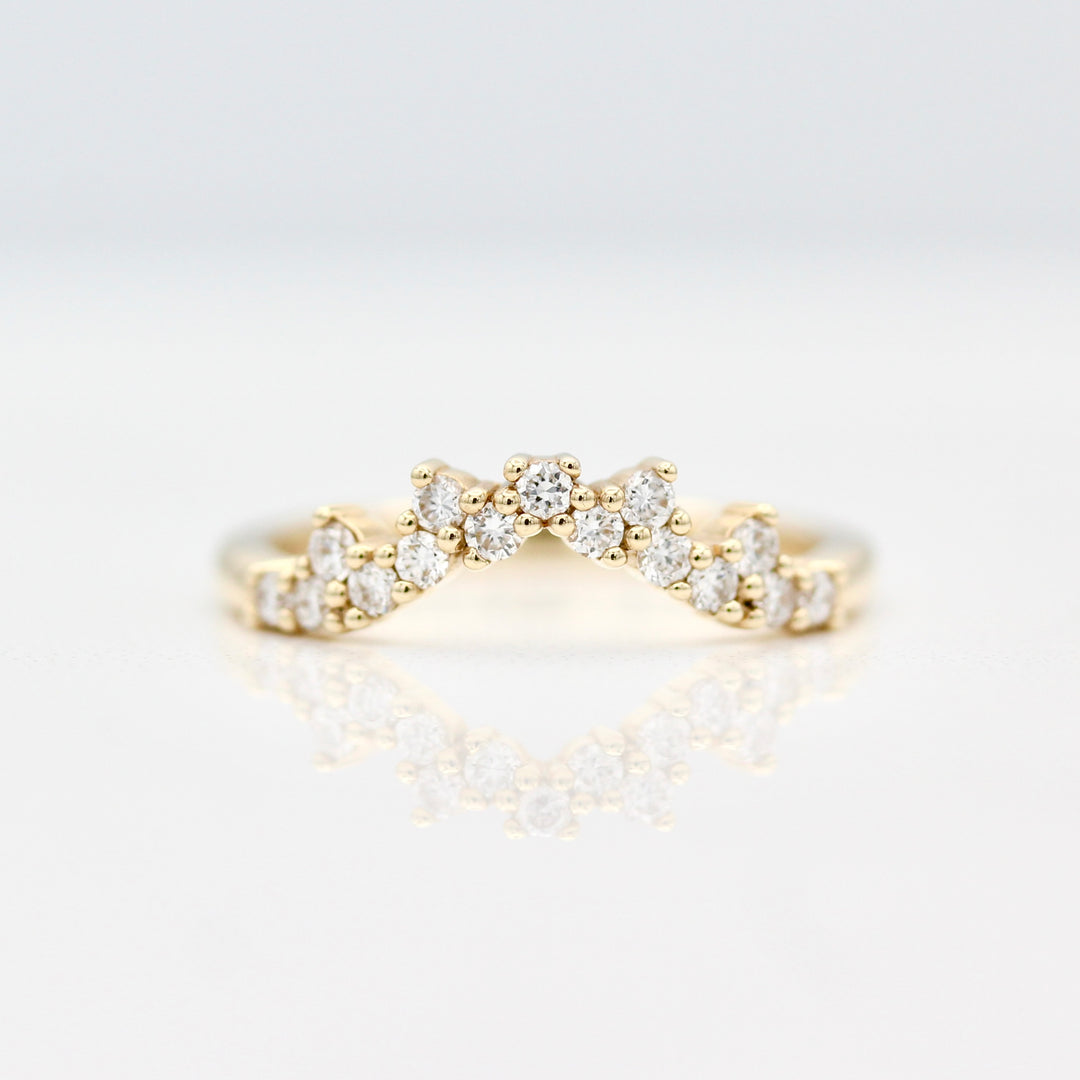 Curved yellow gold wedding band with 15 round diamond accents on a white background