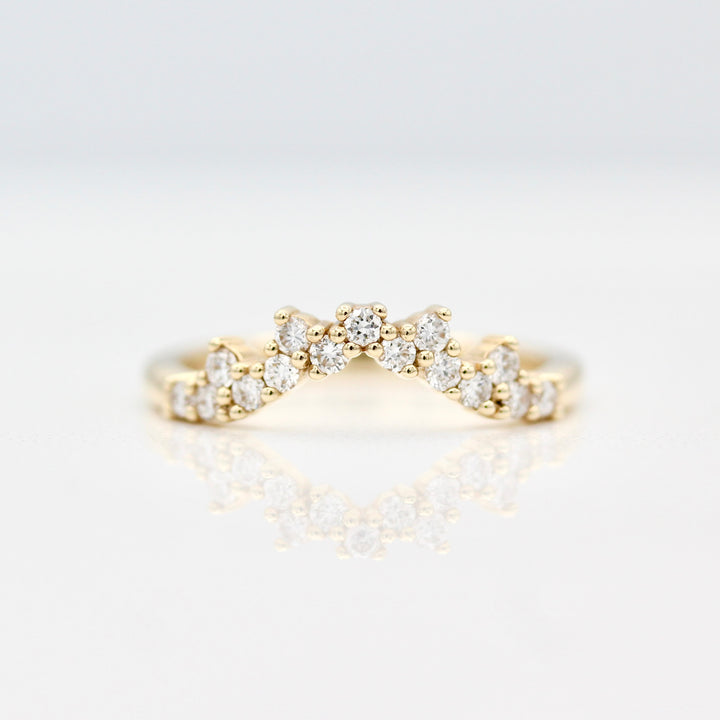 Curved yellow gold wedding band with 15 round diamond accents on a white background