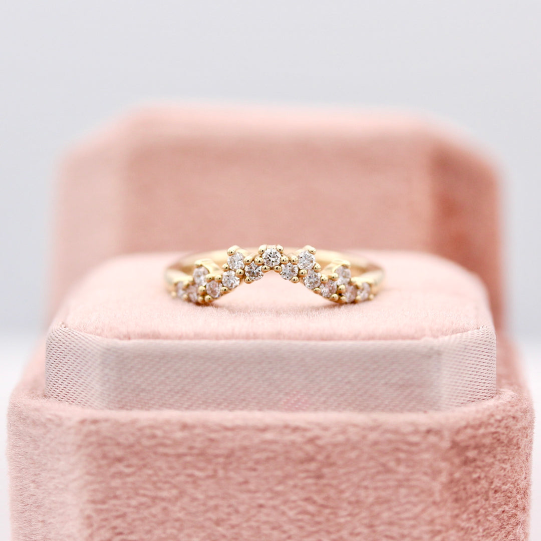 The Nova curved diamond wedding band in  yellow gold resting on a blush pink ring box