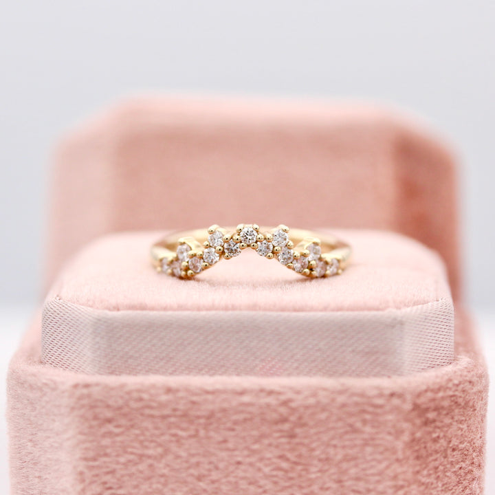 The Nova curved diamond wedding band in  yellow gold resting on a blush pink ring box