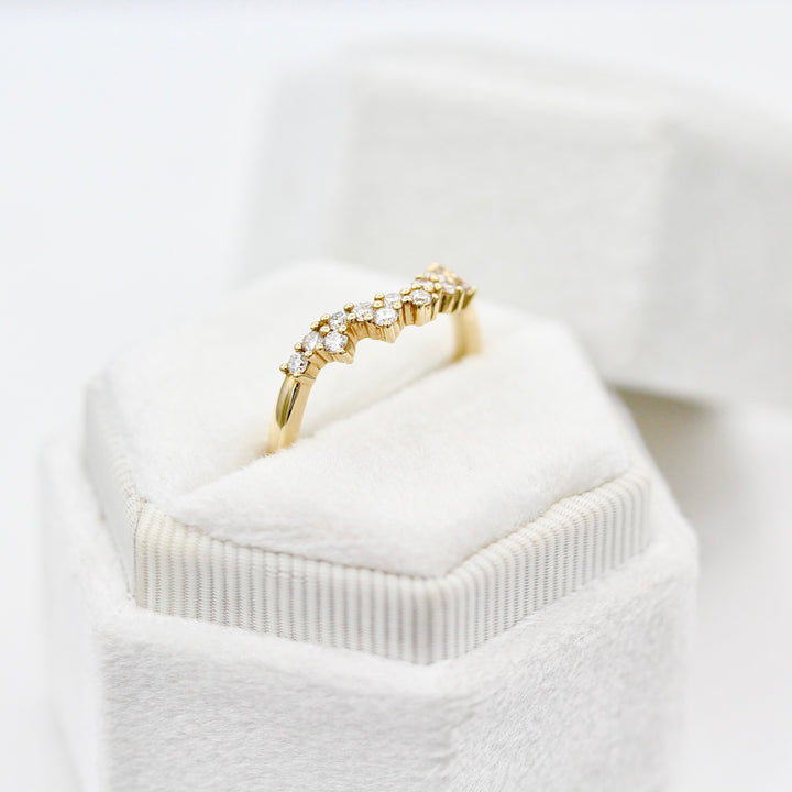 Yellow gold curved wedding band with round diamond melee in a white velvet ring box