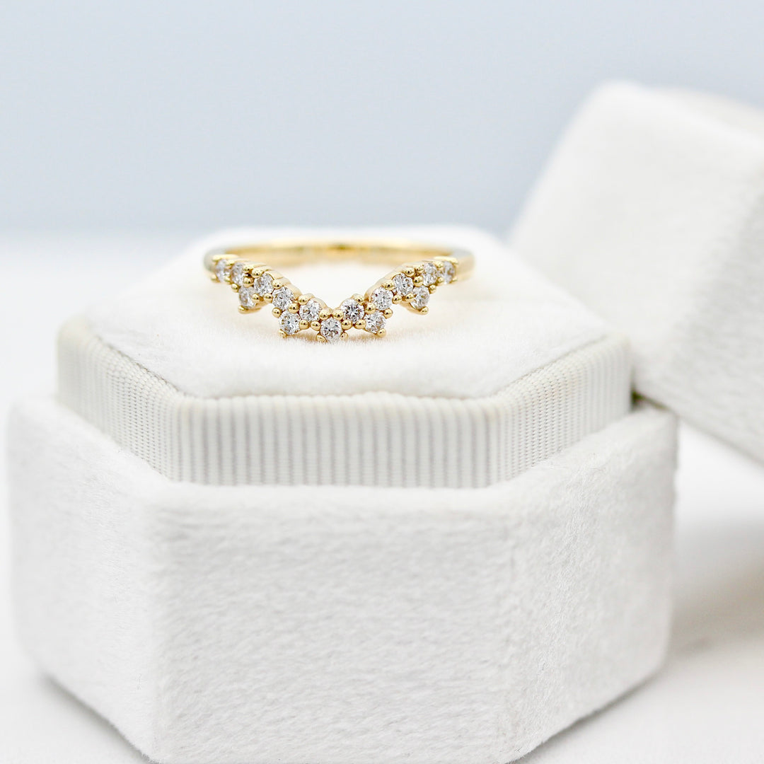 The Nova round diamond wedding band in yellow gold resting on a white velvet ring box with lid