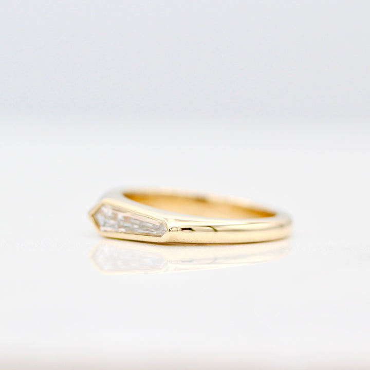 Angled view of the tapered band in yellow gold on a white background