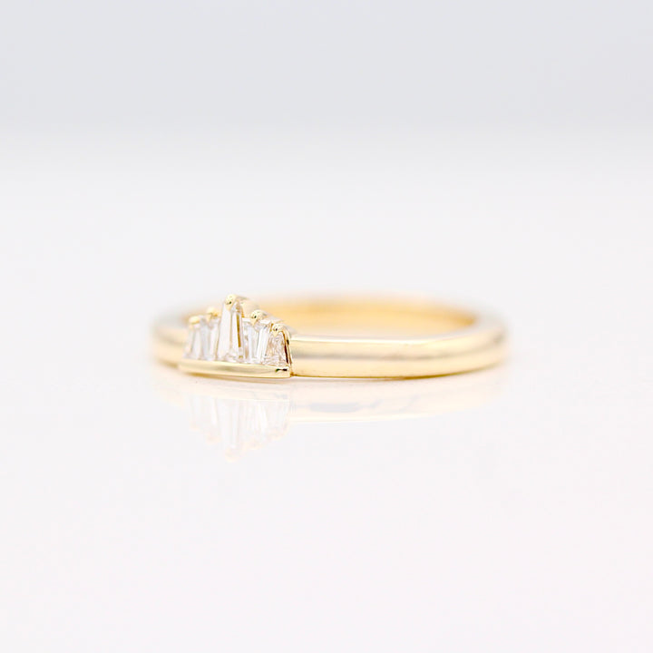 Yellow gold tapered diamond baguette ring with single claw prongs on a neutral background