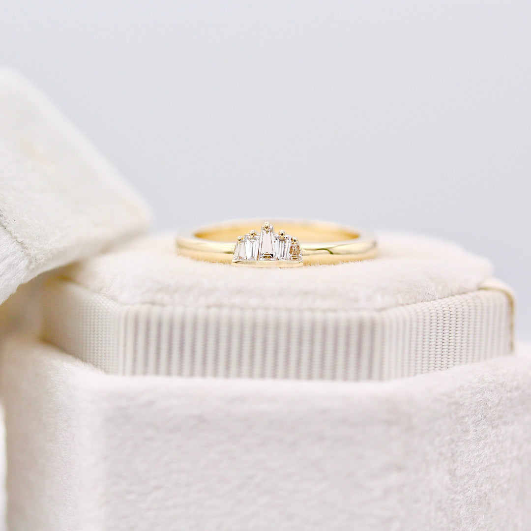 Yellow gold alternating diamond baguette ring with claw prongs and half bezel resting on a white velvet ring box