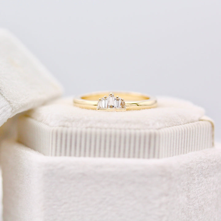 Yellow gold alternating diamond baguette ring with claw prongs and half bezel resting on a white velvet ring box