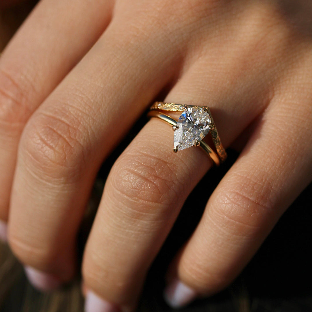 The Willow Wedding Band stacked with a Pear shaped Diamond Engagement Ring on a Glowy Hand.