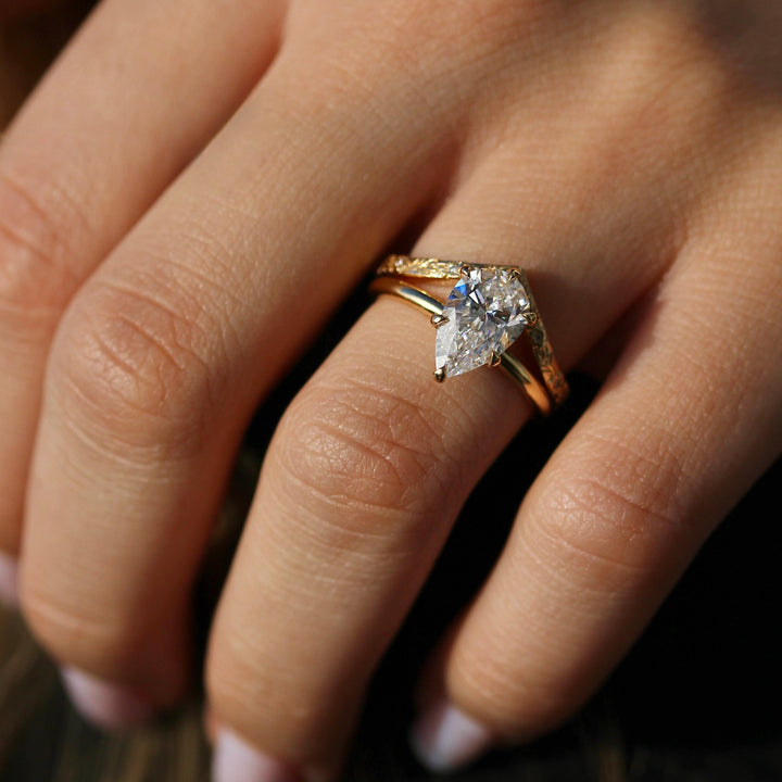 The Willow Wedding Band stacked with a Pear shaped Diamond Engagement Ring on a Glowy Hand.