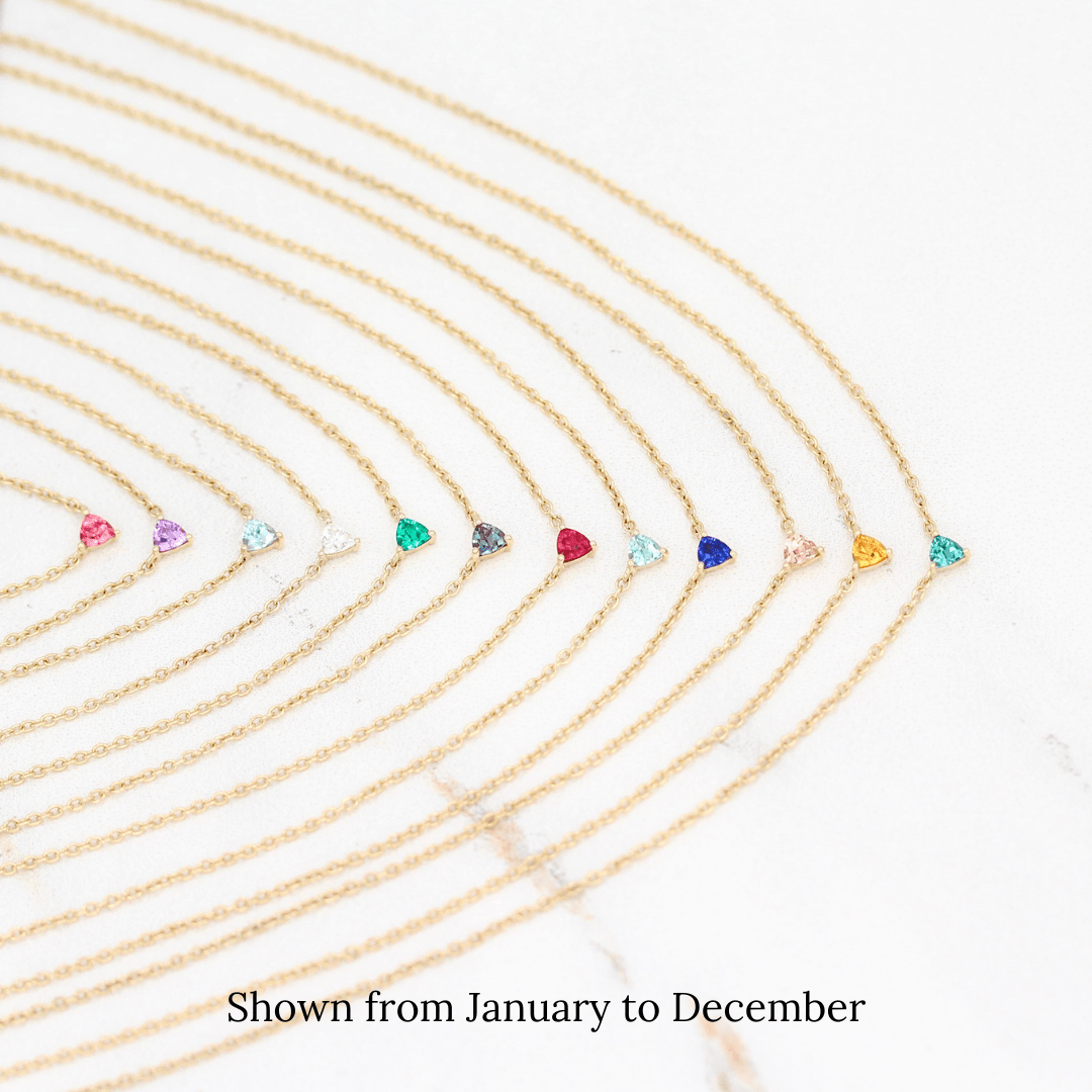 The Tiny Trillion Birthstone Necklaces in Yellow Gold stacked from January to December against a white background