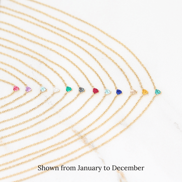The Tiny Trillion Birthstone Necklaces in Yellow Gold stacked from January to December against a white background