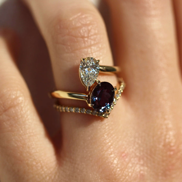 Toi et Moi Diamond and Alexandrite Bypass Ring in yellow gold stacked on a hand with the Diamond V-Band in yellow gold