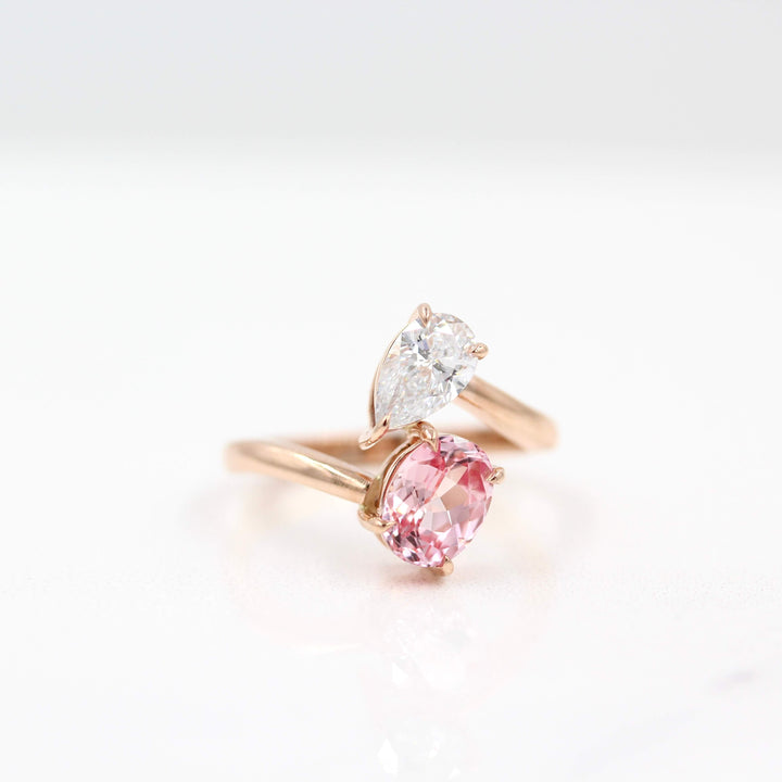 Toi et Moi Diamond and Peachy-Pink Sapphire Bypass Ring in Rose Gold against a white background