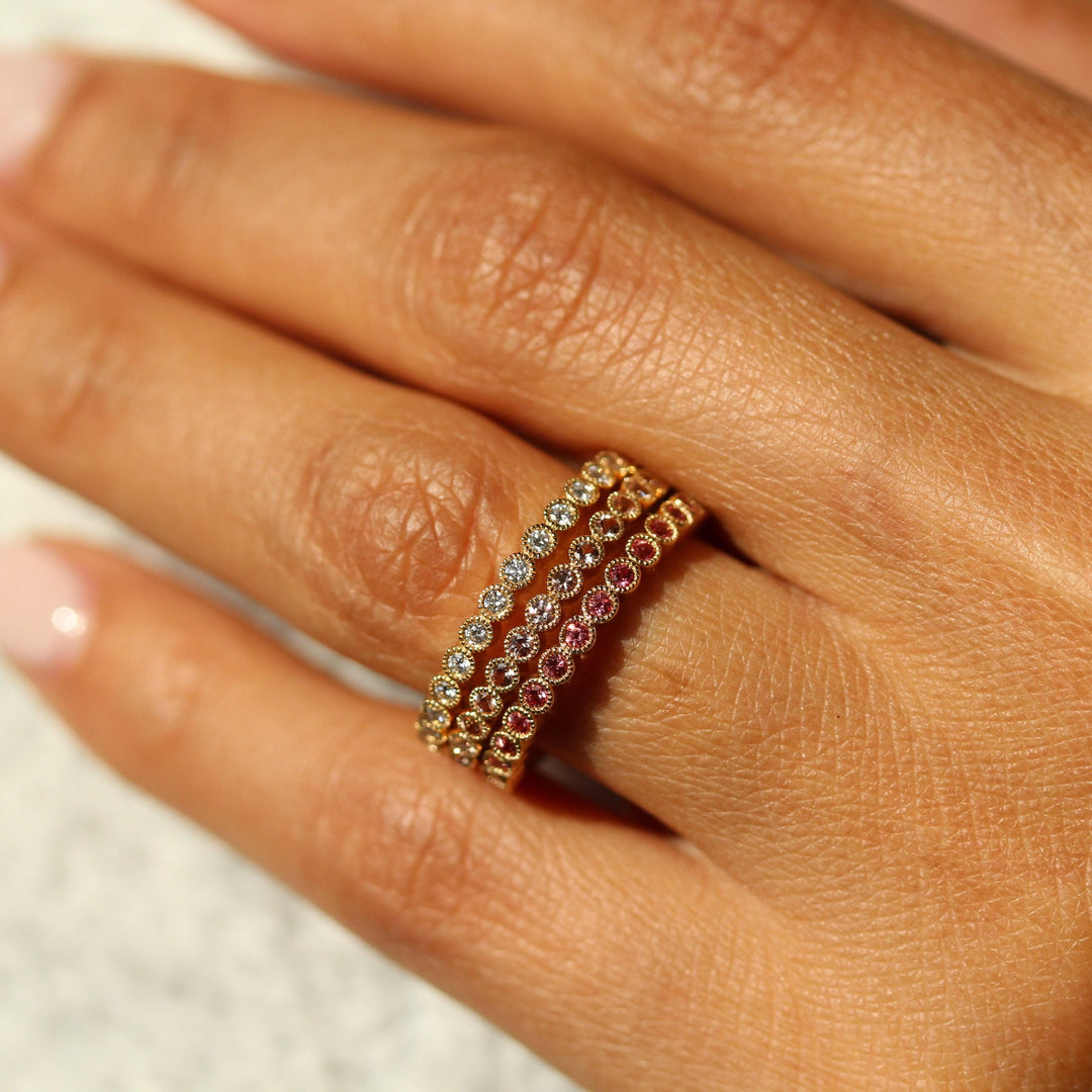 The April Florence Birthstone Wedding Band with Lab-Grown Diamond in Yellow Gold stacked with the June Florence Birthstone Wedding Band with Alexandrite in Yellow Gold and the January Florence Birthstone Wedding Band with Padparadscha Sapphire in Yellow Gold modeled