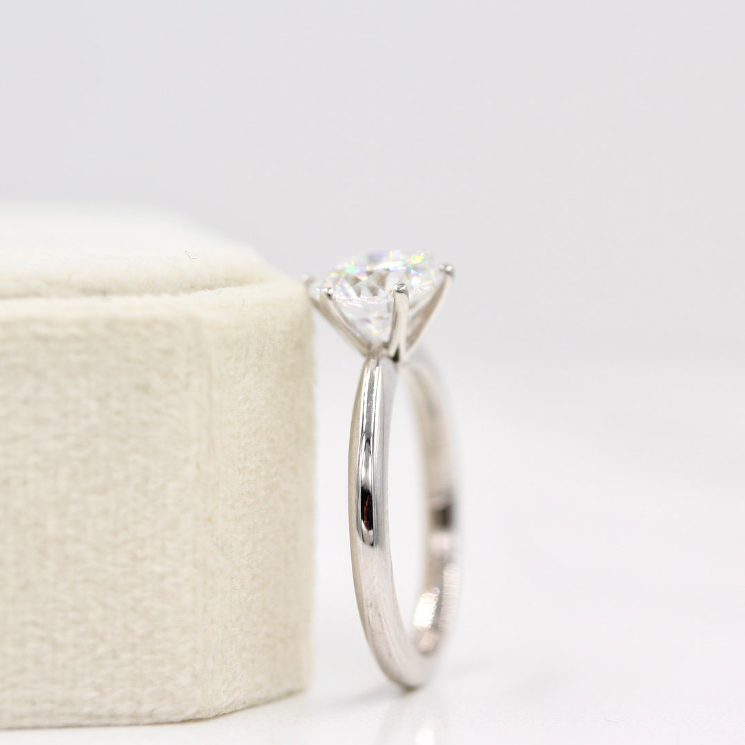 The Audrey Ring in White Gold and 2ct Moissanite leaning against a white velvet ring box
