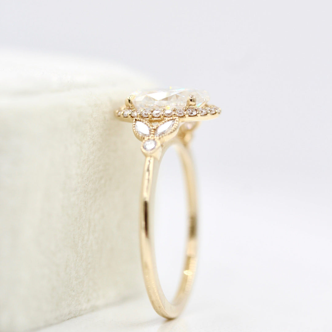 The Cate Ring (Oval) in yellow gold leaning against a white velvet ring box