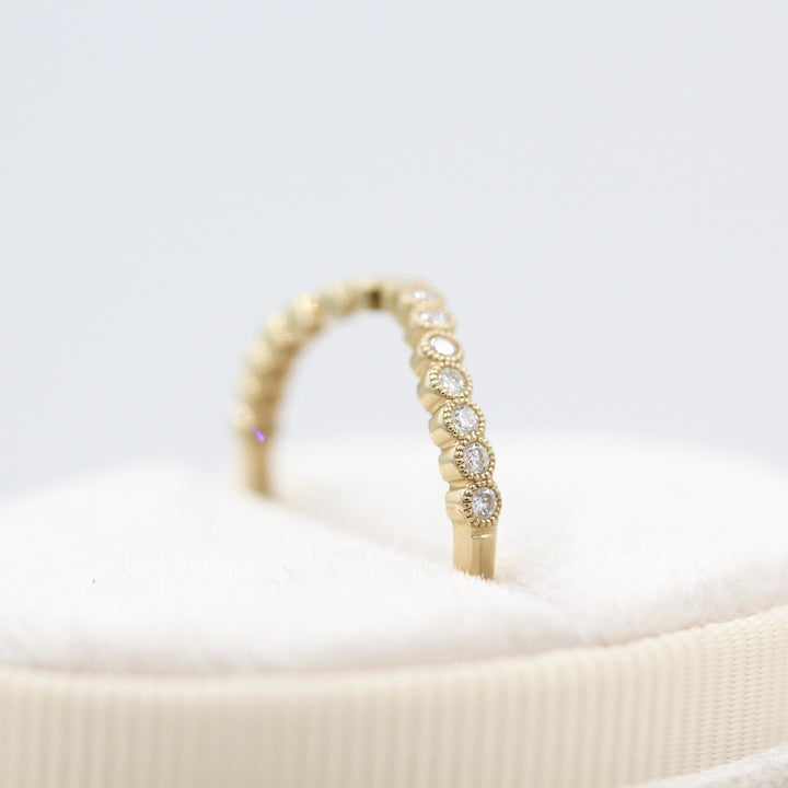 side view of yellow gold contour band with milgrain detail in a white ring box