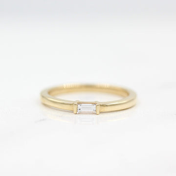 a gold baguette ring on a white surface