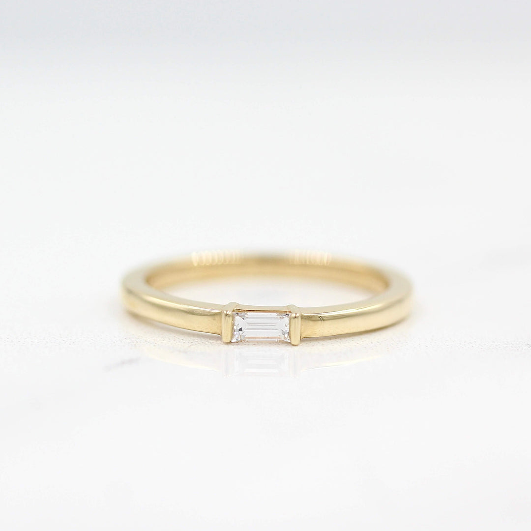 a gold baguette ring on a white surface