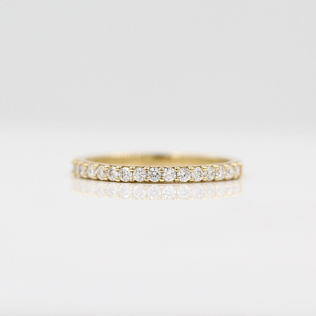 a gold pavé wedding band on a white surface