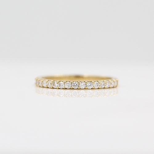 a gold pavé wedding band on a white surface