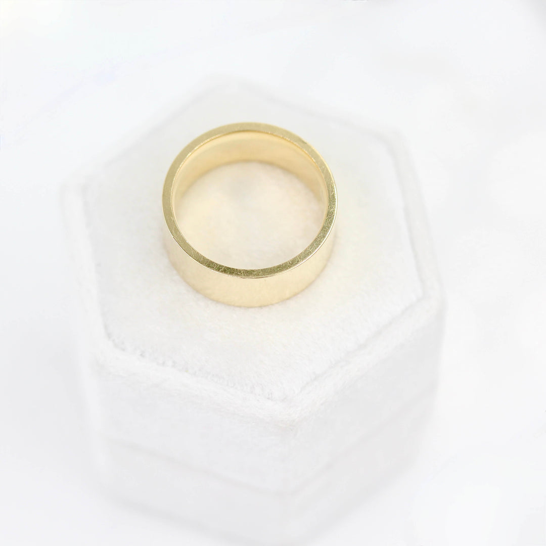 a gold wedding band on a ring box from above