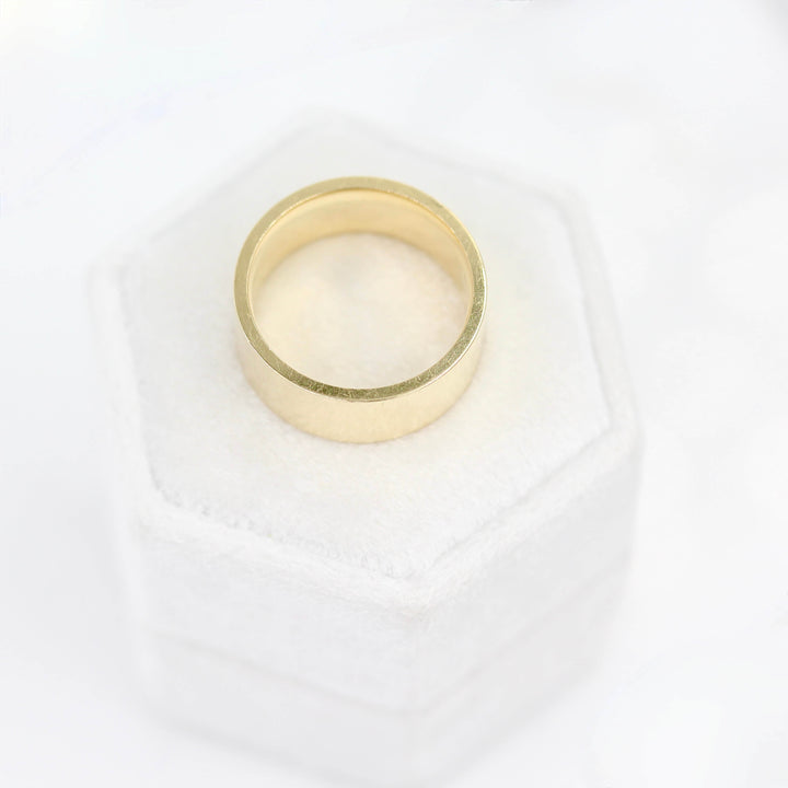 a gold wedding band on a ring box from above