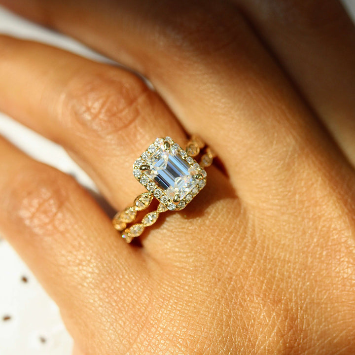 a model wearing an emerald engagement ring and scalloped band